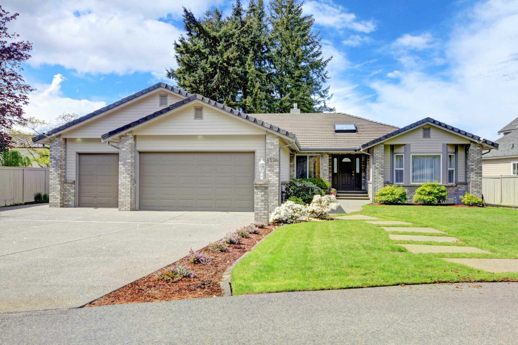 A modern house exterior with a yard and a tree.